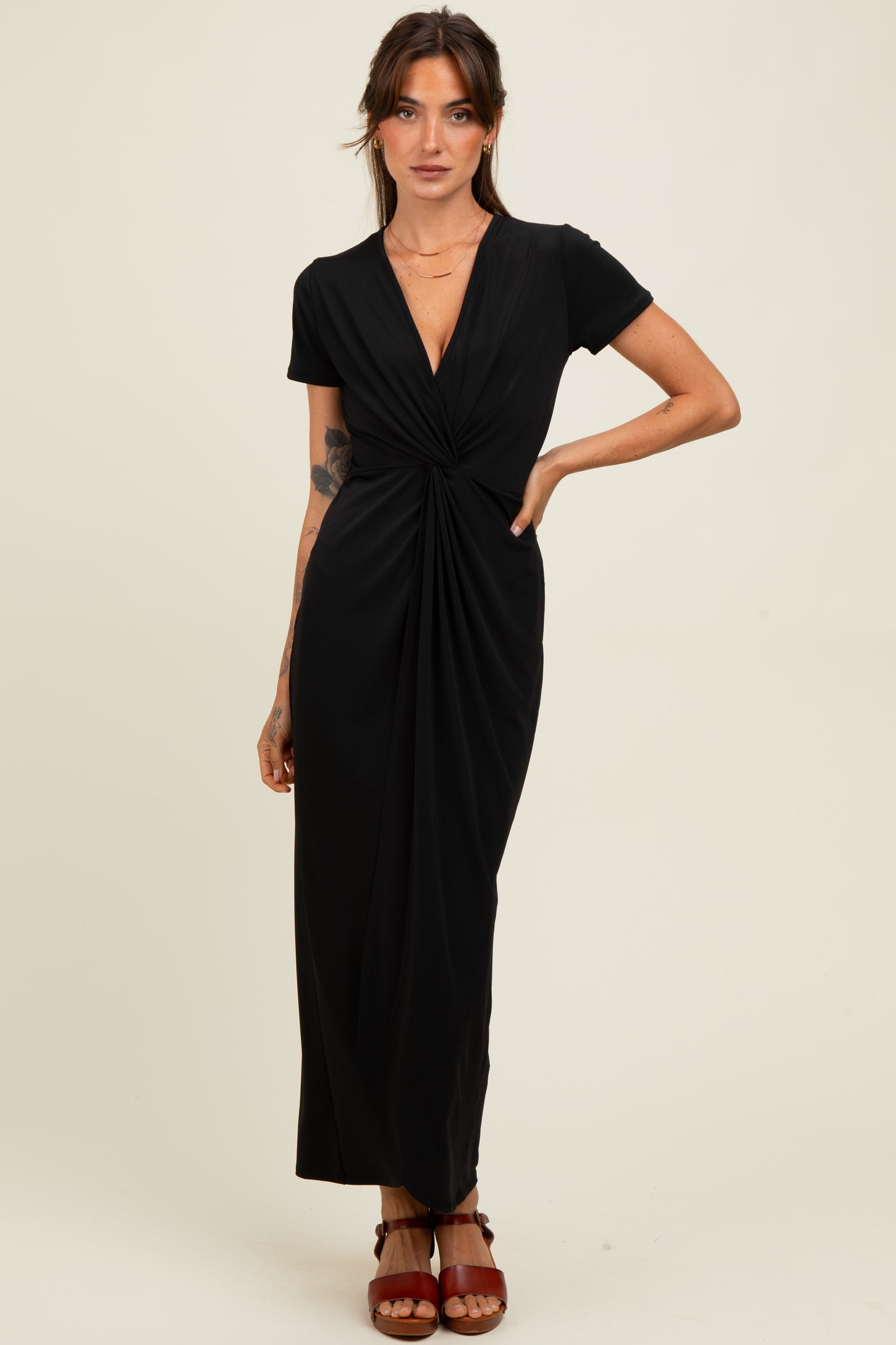 woman wearing a black short sleeve maxi dress with a twisted front detail