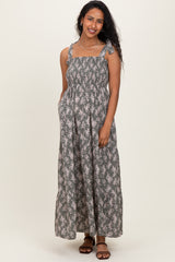 woman wearing a floral patterned gray maternity maxi dress with adjustable straps and pockets