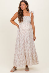 woman wearing a light beige floral print maternity maxi dress with square neckline and tie shoulder straps, baby bump visible
