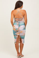 woman wearing a multicolored maternity dress with crossback straps and a mid-length design