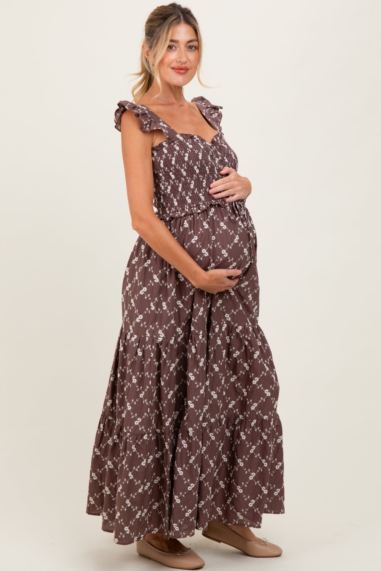 woman wearing a brown floral smocked maternity maxi dress and holding her baby bump