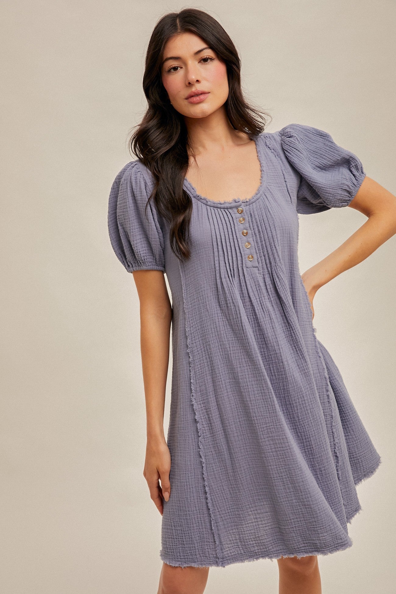 woman wearing a short lavender puff sleeve dress with a button detail and a relaxed fit