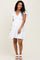 woman wearing a white floral maternity dress with a v-neck and ruffled sleeves, revealing her baby bump