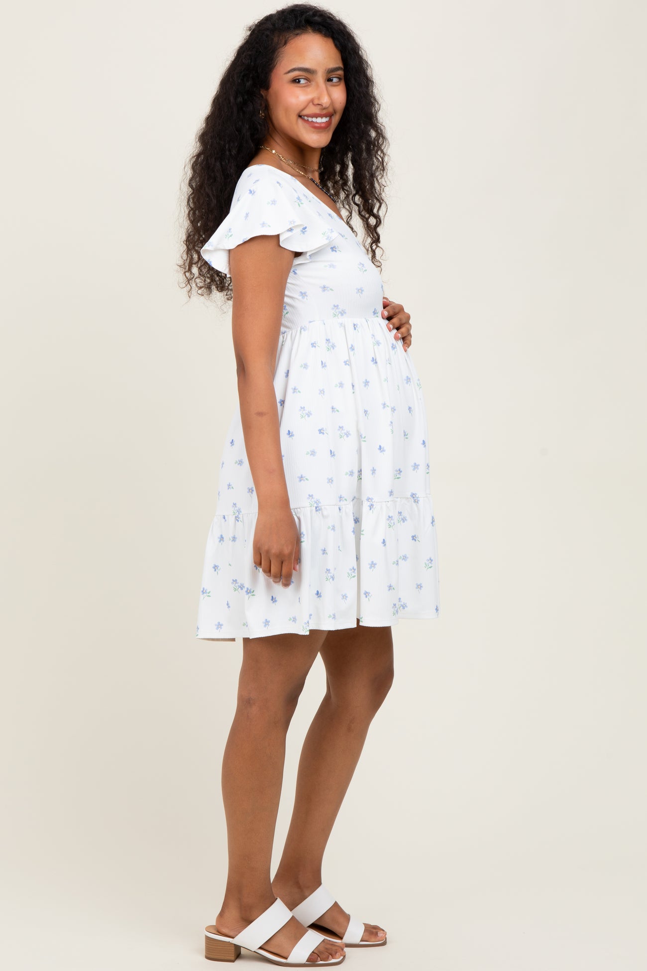woman wearing a white floral maternity dress with ruffle sleeves and a visible baby bump