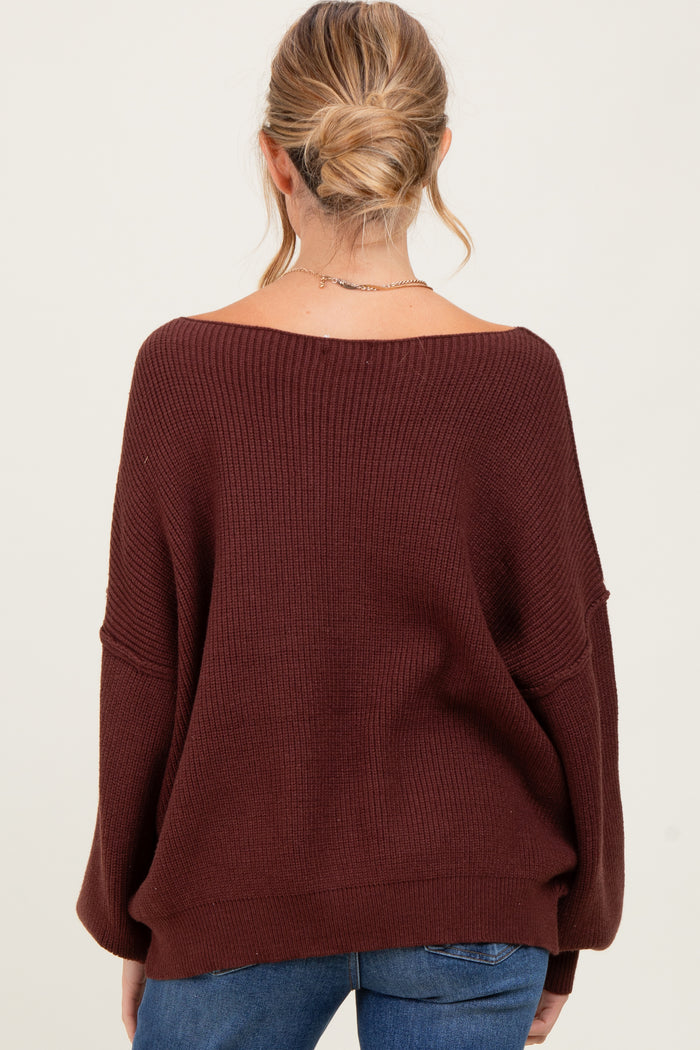 woman wearing a burgundy oversized maternity sweater viewed from the back, showing relaxed fit and ribbed texture