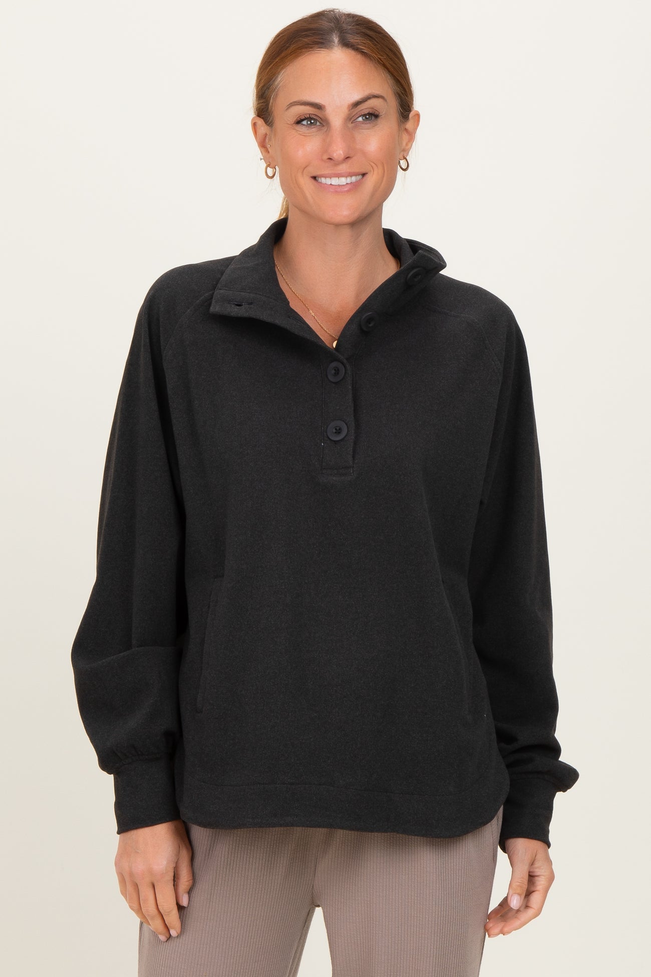 woman wearing a black pullover sweatshirt with a collar and button details, smiling at the camera
