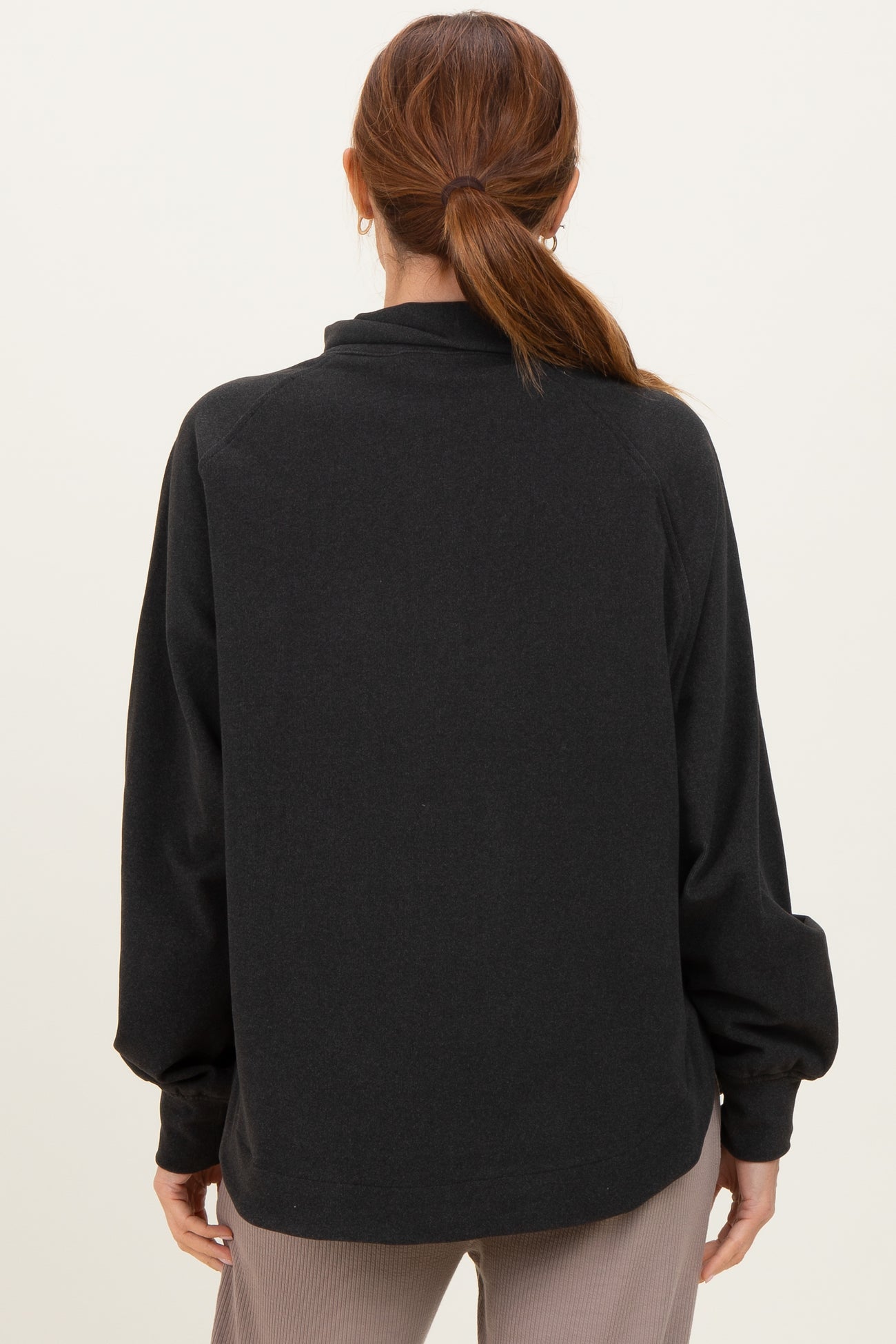 woman wearing a black pullover sweatshirt with a relaxed fit and long sleeves, viewed from the back