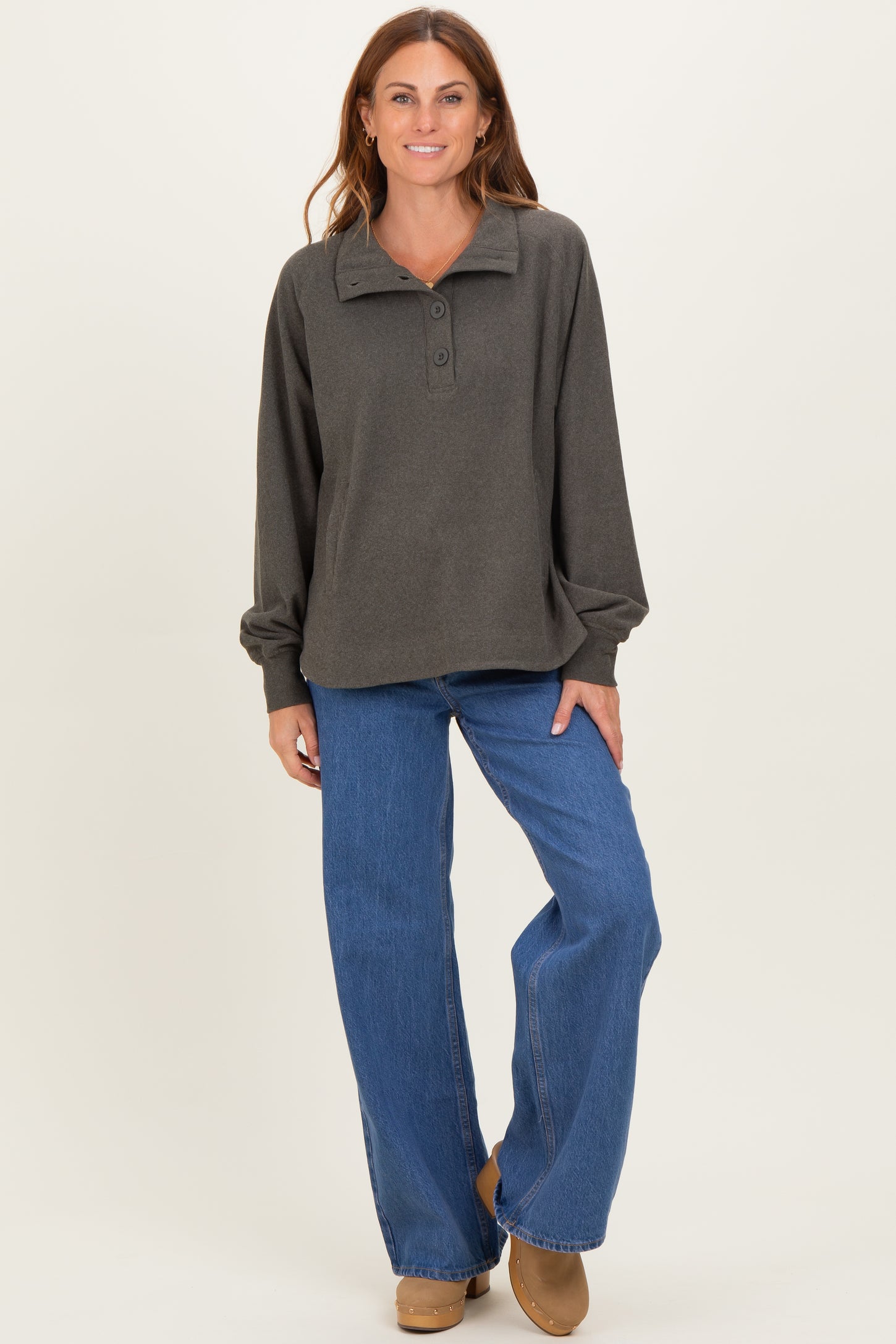woman wearing a dark gray button-up long sleeve pullover with a collar and wide-leg blue jeans