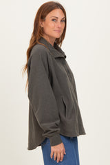 woman wearing a dark gray oversized pullover with button details and a front pocket, styled with blue jeans