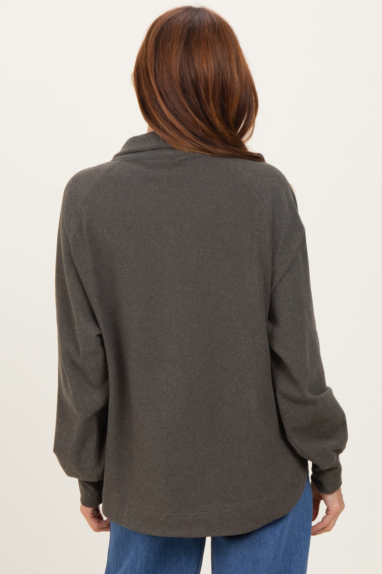 woman wearing a dark green oversized long sleeve top, shown from the back with a relaxed fit and rolled sleeves