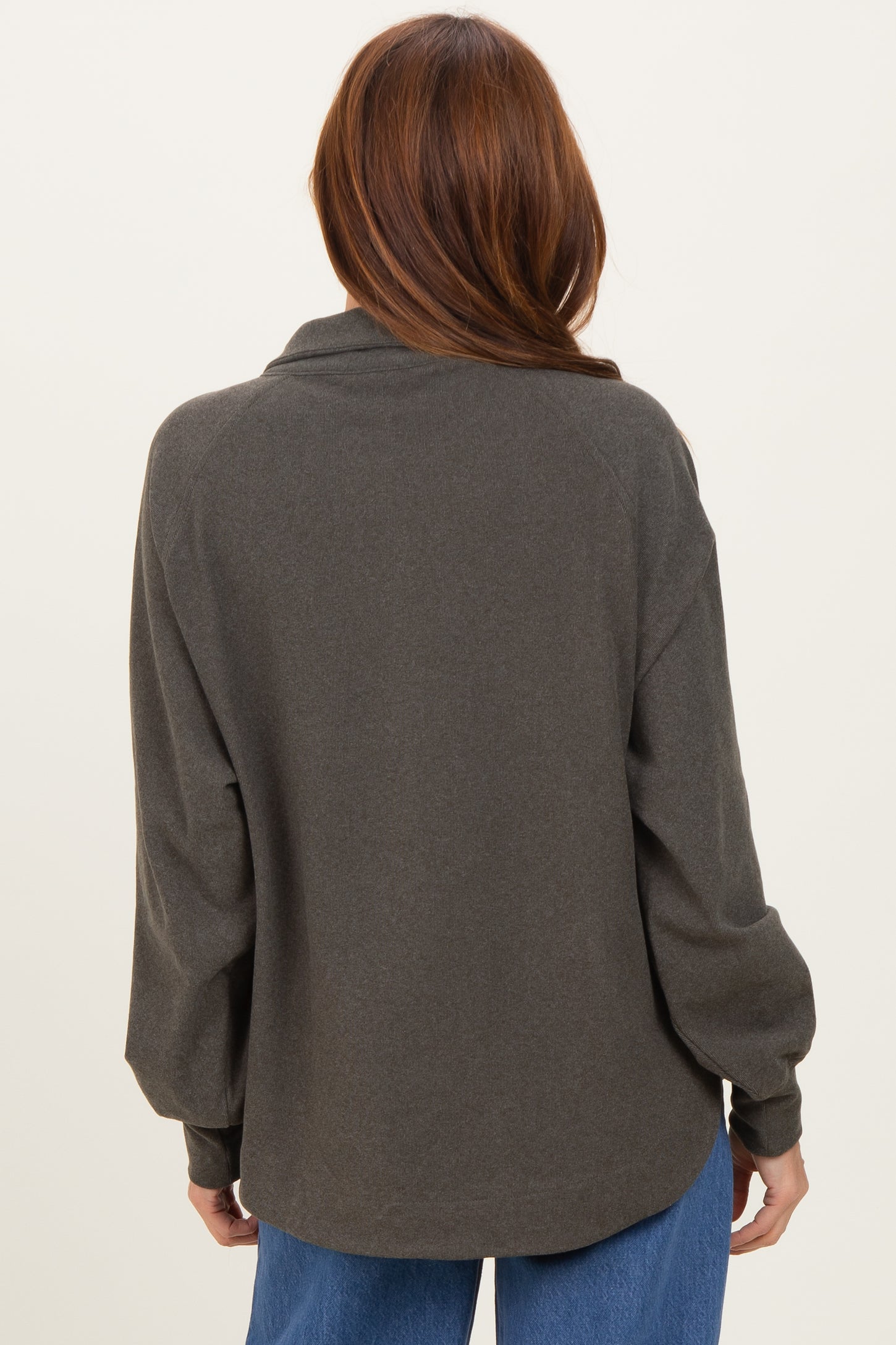 woman wearing a dark green oversized long sleeve top, shown from the back with a relaxed fit and rolled sleeves