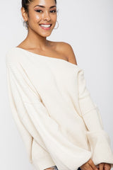 woman wearing a cream off-the-shoulder oversized sweater with long sleeves and a relaxed fit