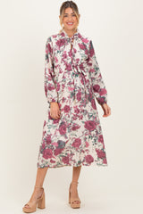 woman wearing a floral print maternity dress with long sleeves and a tied waist, highlighting her baby bump