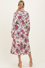 woman wearing a floral long sleeve maternity dress with a cinched waist and ankle-length skirt, showing a baby bump