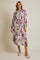 woman wearing a floral midi dress with purple and green flowers, tied at the waist, and sandals