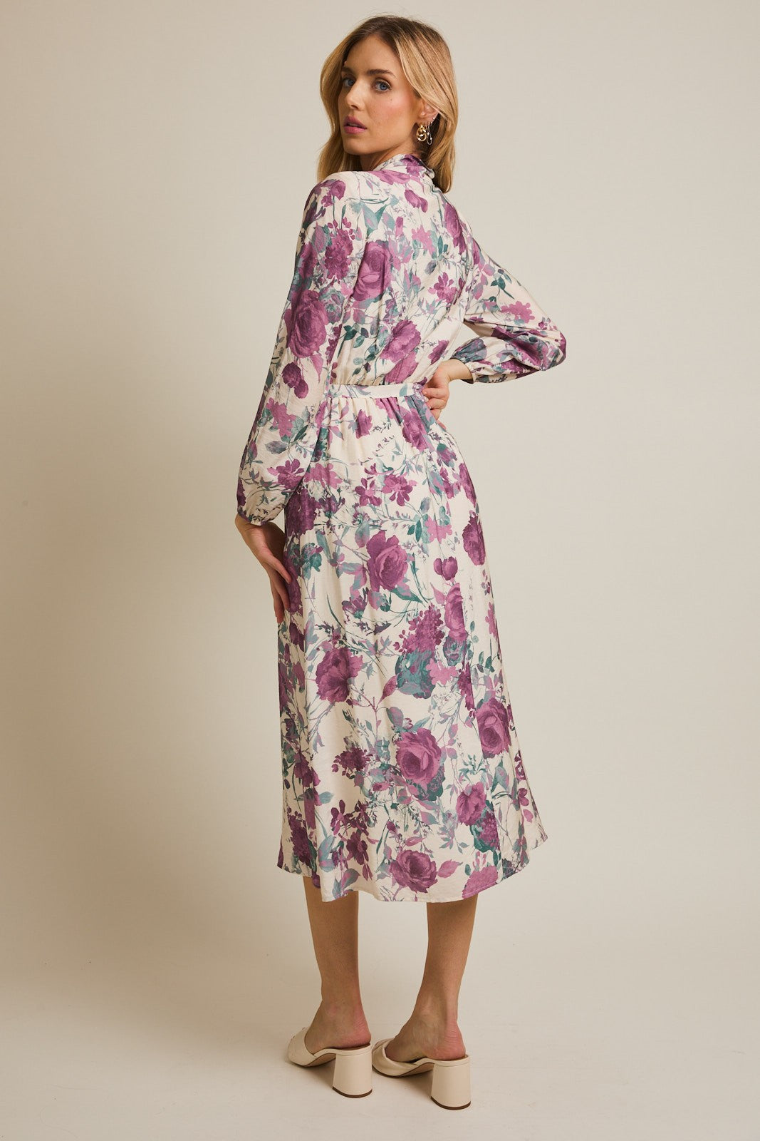 woman wearing a floral print long sleeve dress with a tie waist and a mid-length hem, viewed from the back