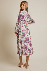 woman wearing a floral print long sleeve dress with a tie waist and a mid-length hem, viewed from the back