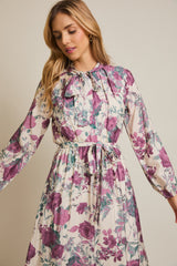 woman wearing a floral long sleeve dress with a bow tie neckline and a cinched waist