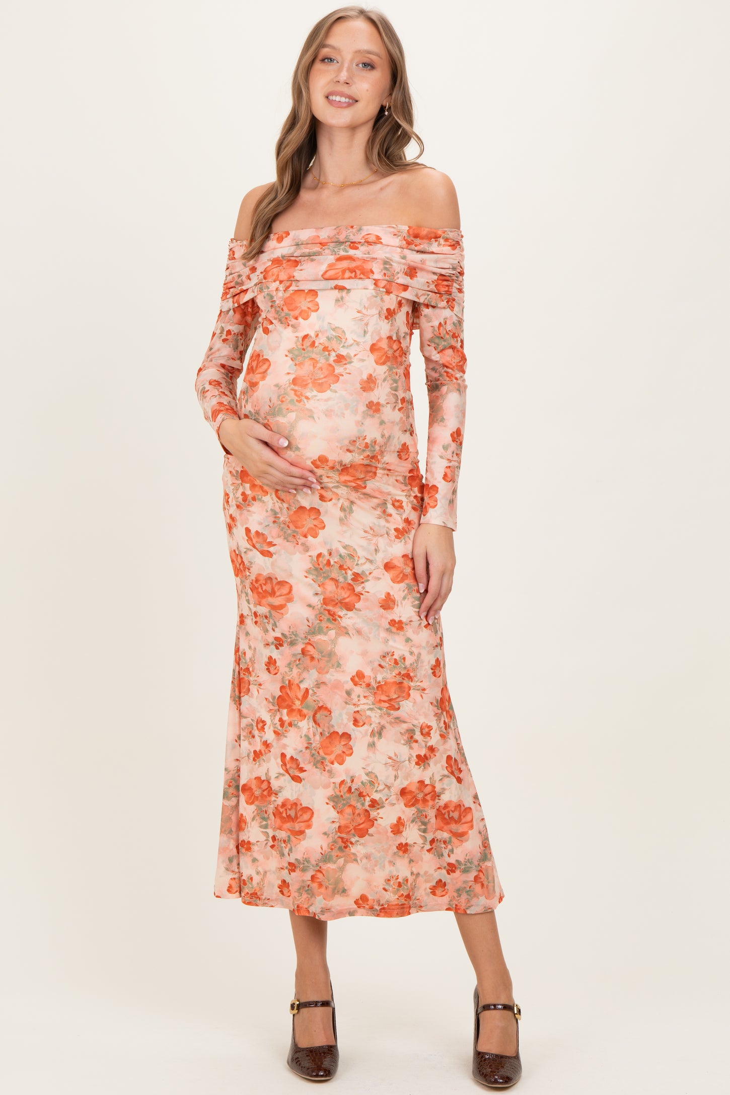 woman wearing a floral off-the-shoulder maternity dress with long sleeves and a visible baby bump