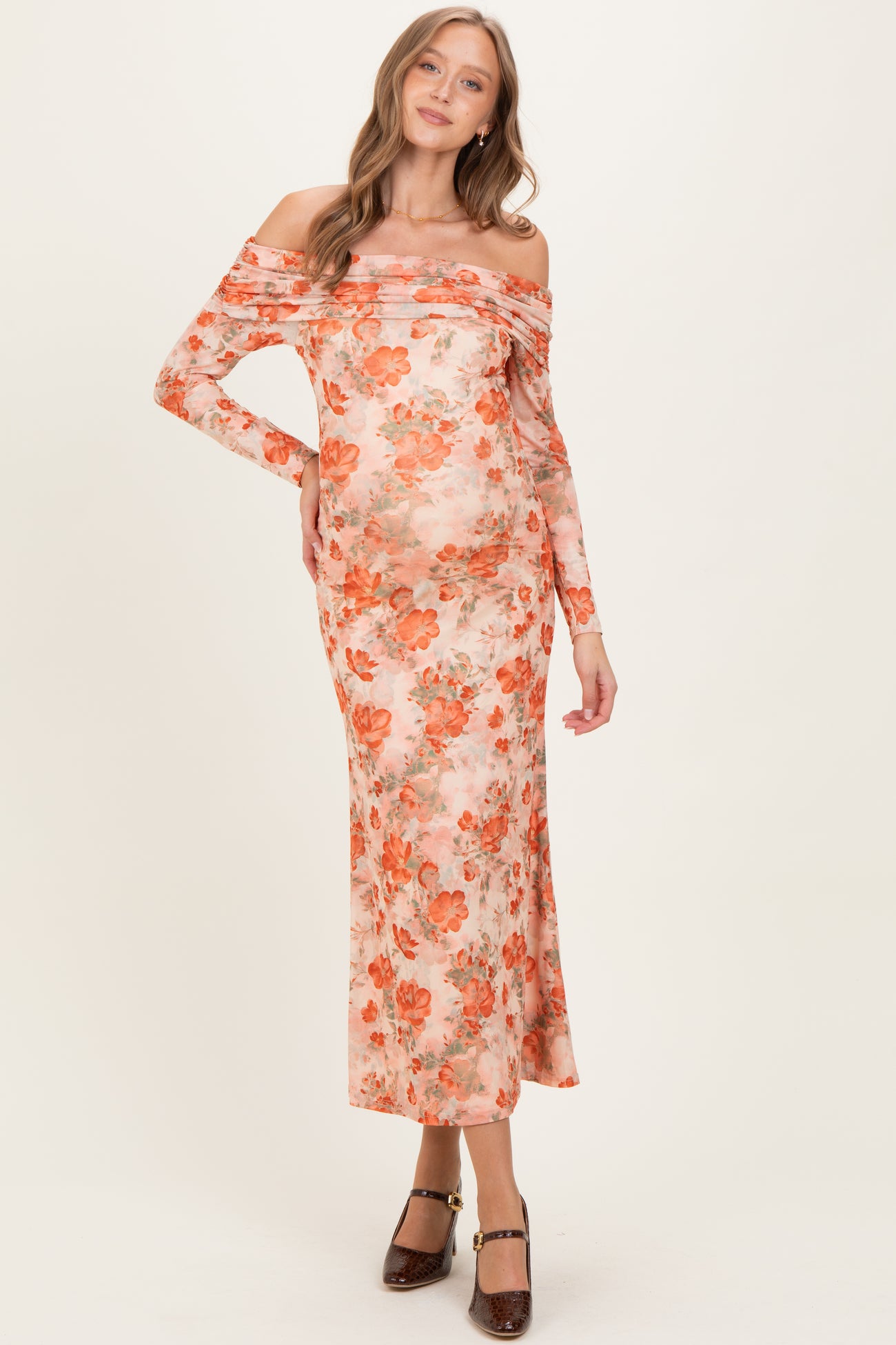 woman wearing a floral off-the-shoulder maternity dress with long sleeves and a visible baby bump