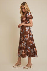 woman wearing a brown floral maxi dress with puff sleeves and a tiered skirt, standing sideways