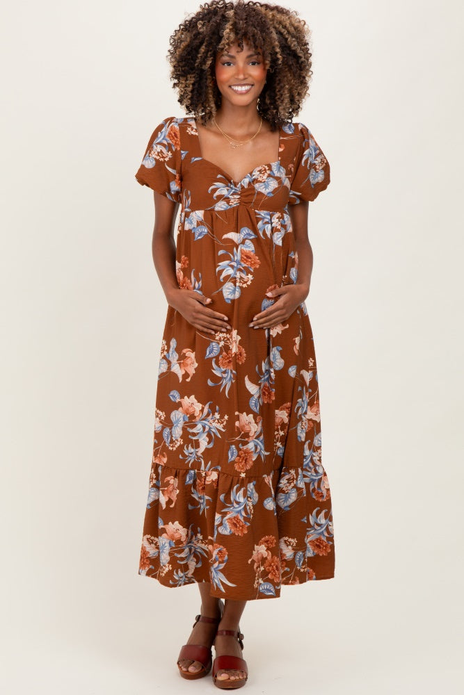 woman wearing a brown floral maternity maxi dress and holding her baby bump