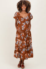 woman wearing a brown floral maternity maxi dress and holding her baby bump