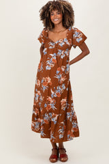 woman wearing a brown floral maternity maxi dress with puff sleeves and a tie-front detail, showcasing her baby bump