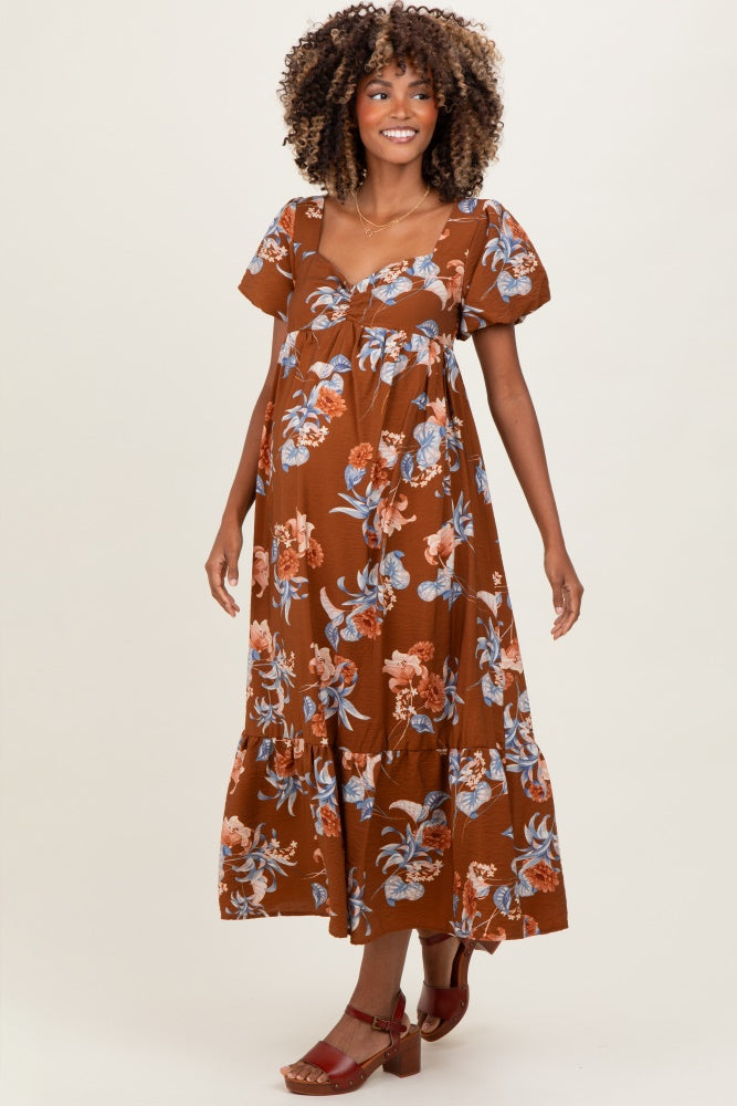 woman wearing a brown floral maternity dress with short puff sleeves and a tie front, showcasing her baby bump