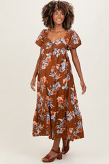woman wearing a brown floral maternity dress with short puff sleeves and a tie front, showcasing her baby bump