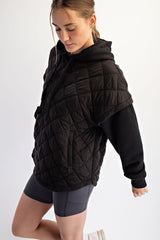 woman wearing a black quilted oversized hoodie with short sleeves and side pockets paired with gray shorts