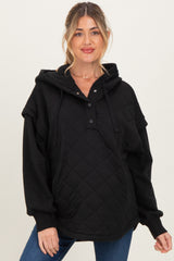 woman wearing a black quilted maternity hoodie with a henley neckline and oversized fit, showing a baby bump