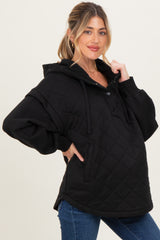 woman wearing a black quilted maternity hoodie with a button detail and oversized fit, showing her baby bump