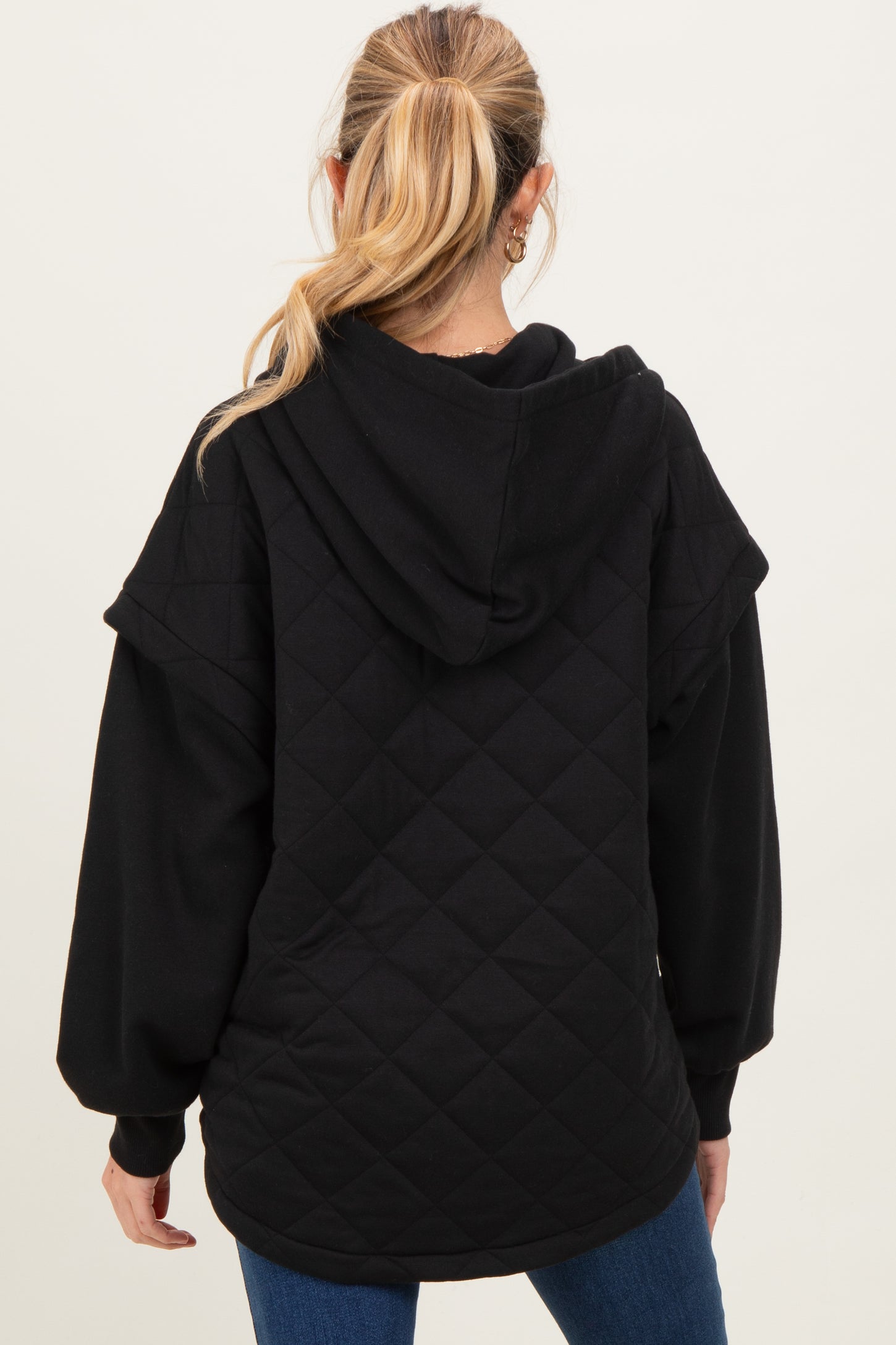 woman wearing a black quilted maternity hoodie with a hood, shown from the back