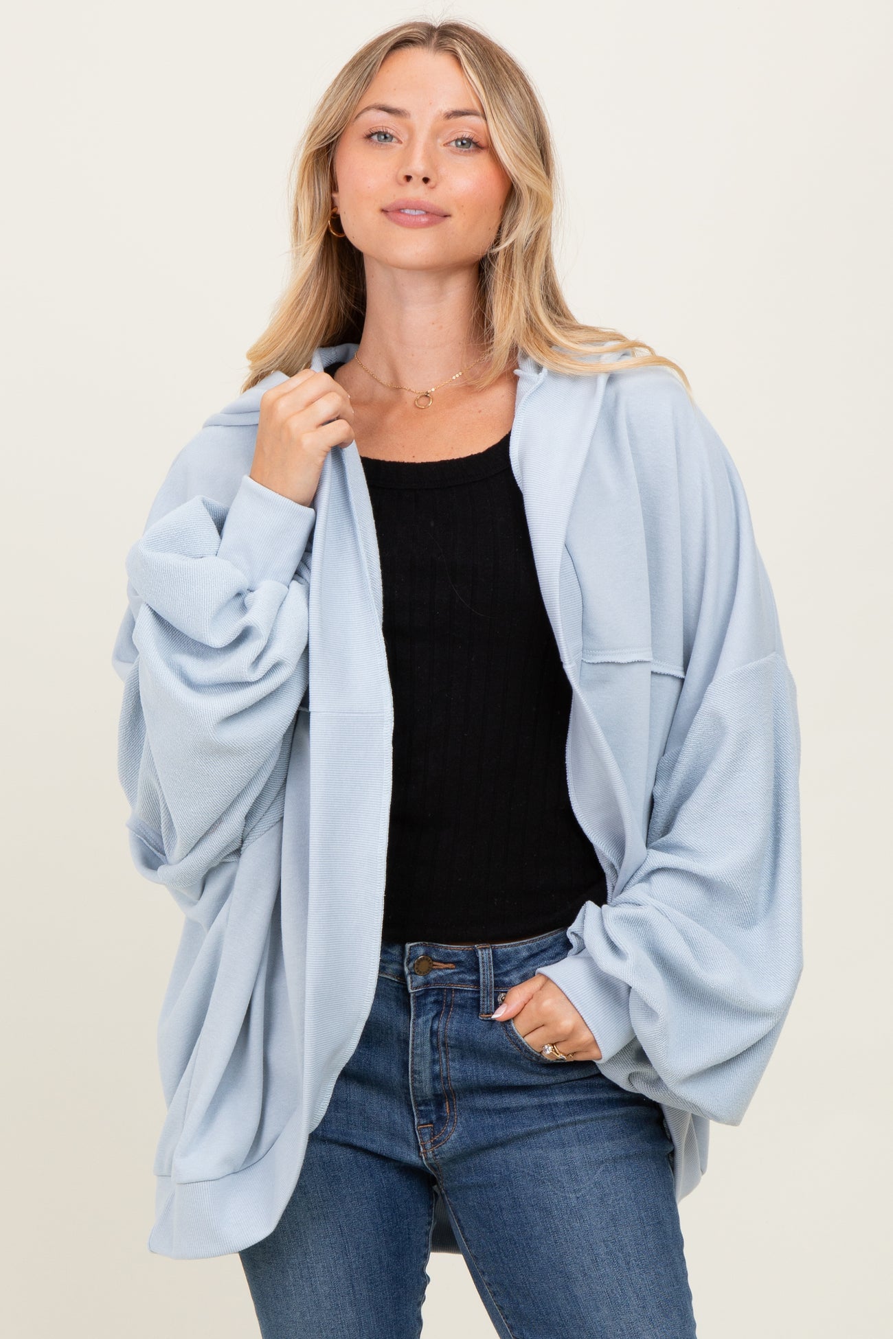 woman wearing a light blue oversized sweatshirt with long sleeves and a relaxed fit, paired with jeans