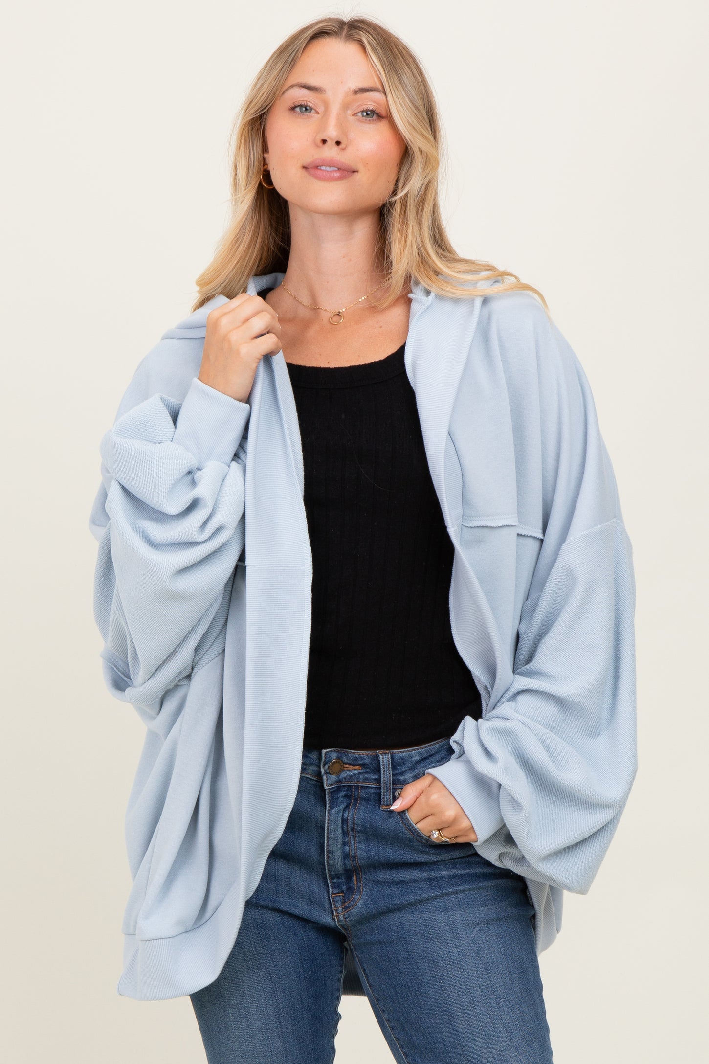 woman wearing a light blue oversized sweatshirt with long sleeves and a relaxed fit, paired with jeans