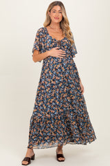 woman wearing a navy blue floral maternity maxi dress and holding her baby bump
