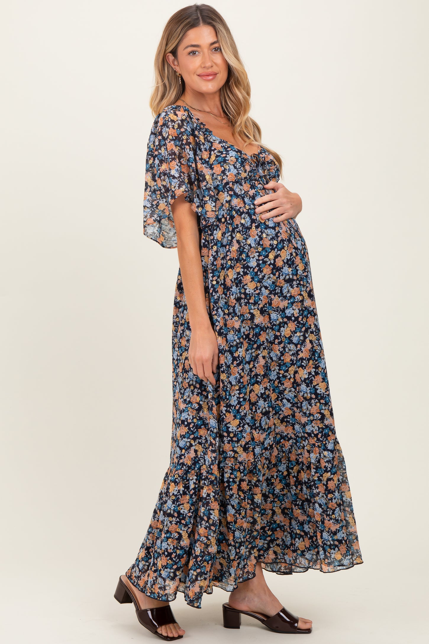 woman wearing a floral navy blue maternity maxi dress and holding her baby bump