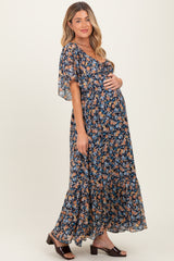 woman wearing a floral navy blue maternity maxi dress and holding her baby bump