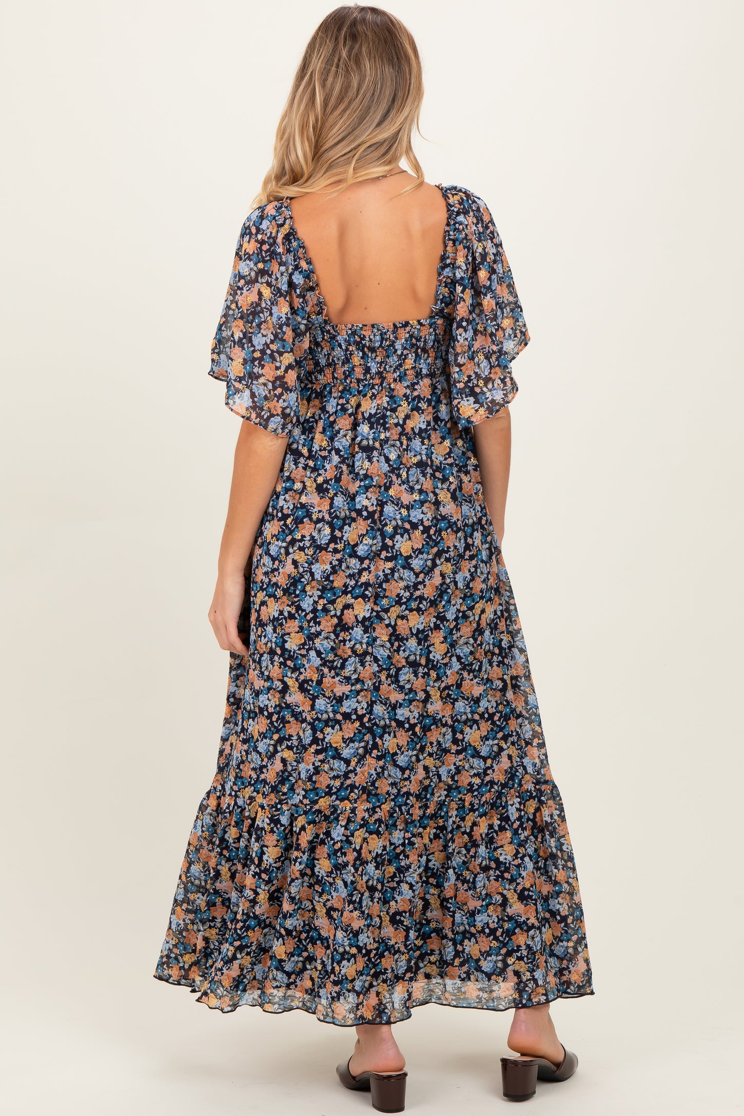 woman wearing a floral print maternity maxi dress with short flutter sleeves and a smocked back