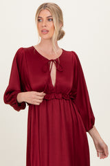 woman wearing a burgundy long sleeve dress with a keyhole neckline and puff sleeves