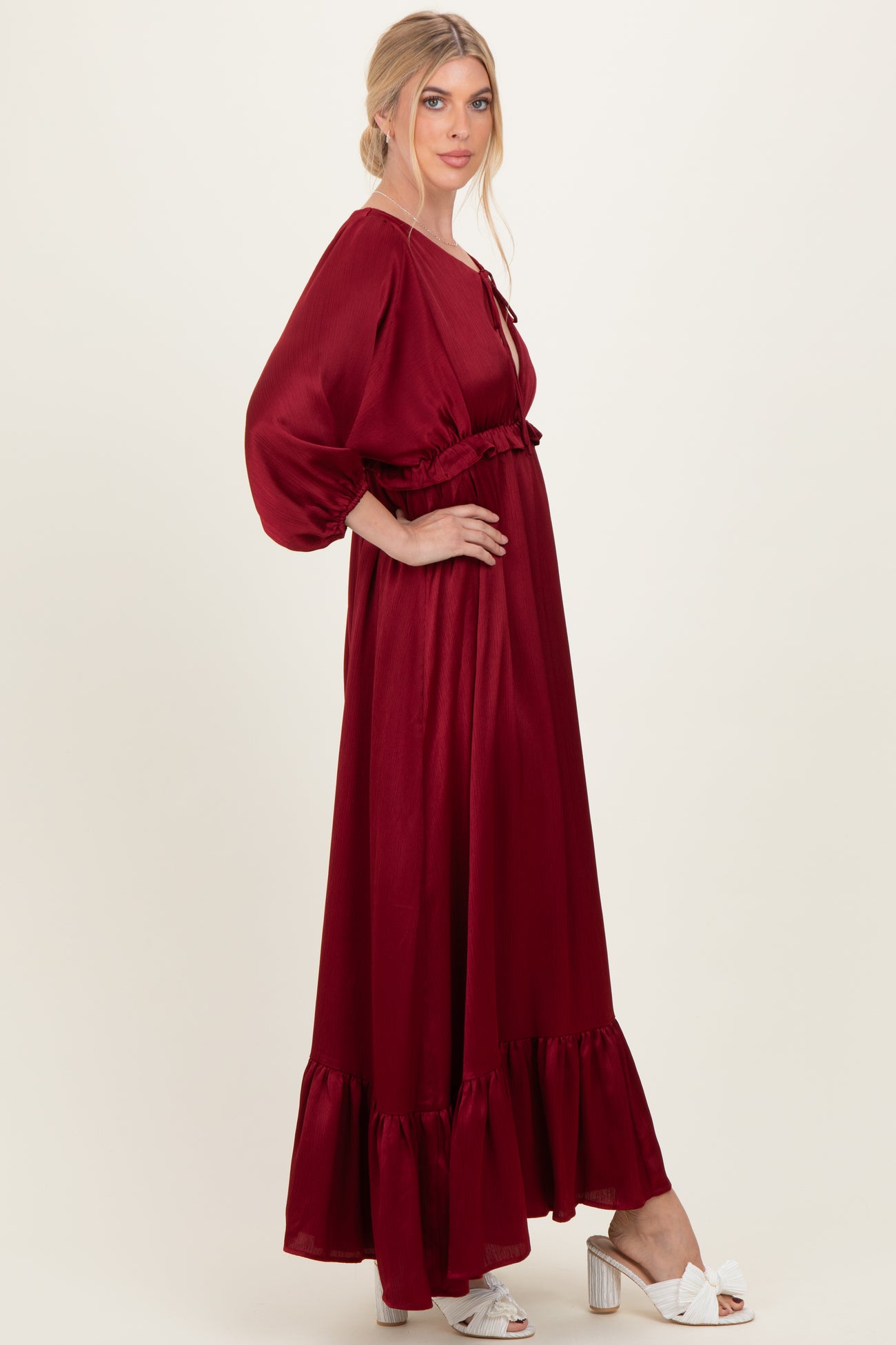 woman wearing a burgundy long sleeve maxi dress with ruffle hem and waist detail