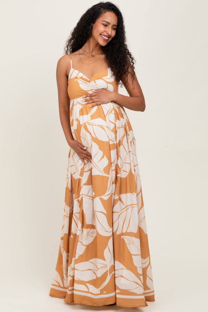 woman wearing a floral patterned yellow maternity maxi dress and holding her baby bump
