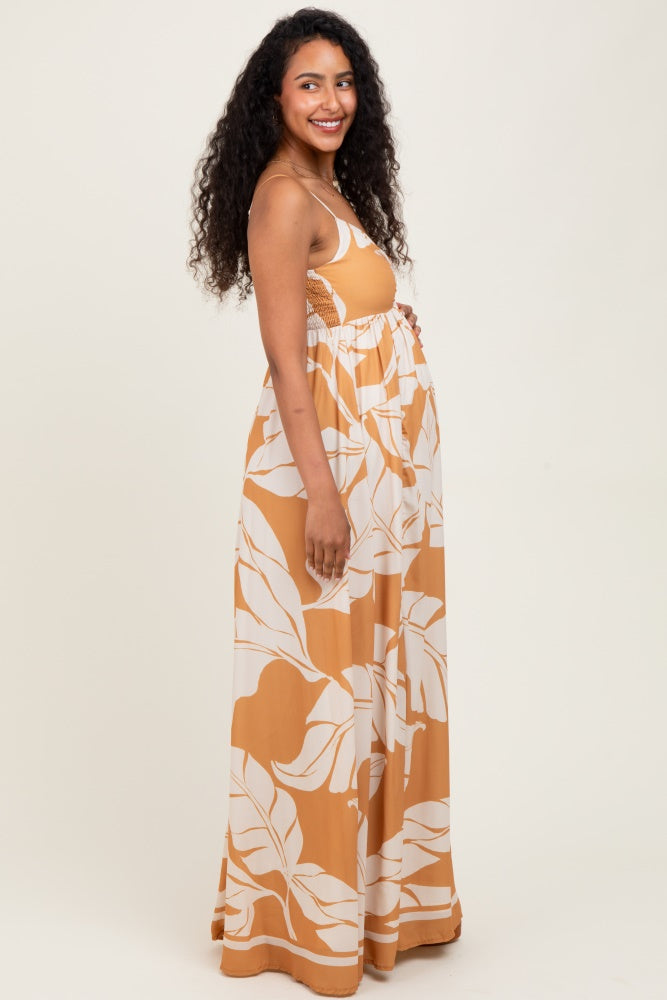 woman wearing a maternity maxi dress with a yellow and white leaf print, showing her baby bump