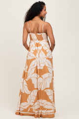 woman wearing a back view of a brown and white floral maternity maxi dress with adjustable straps