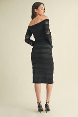 woman wearing a black off-the-shoulder lace midi dress with long sleeves and a fitted silhouette