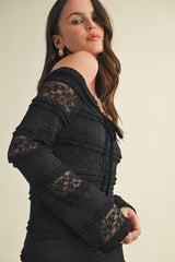 woman wearing a black off-the-shoulder dress with lace detailing and bell sleeves
