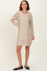 woman wearing a beige knitted sweater dress with cable knit pattern and long sleeves, standing with a smile