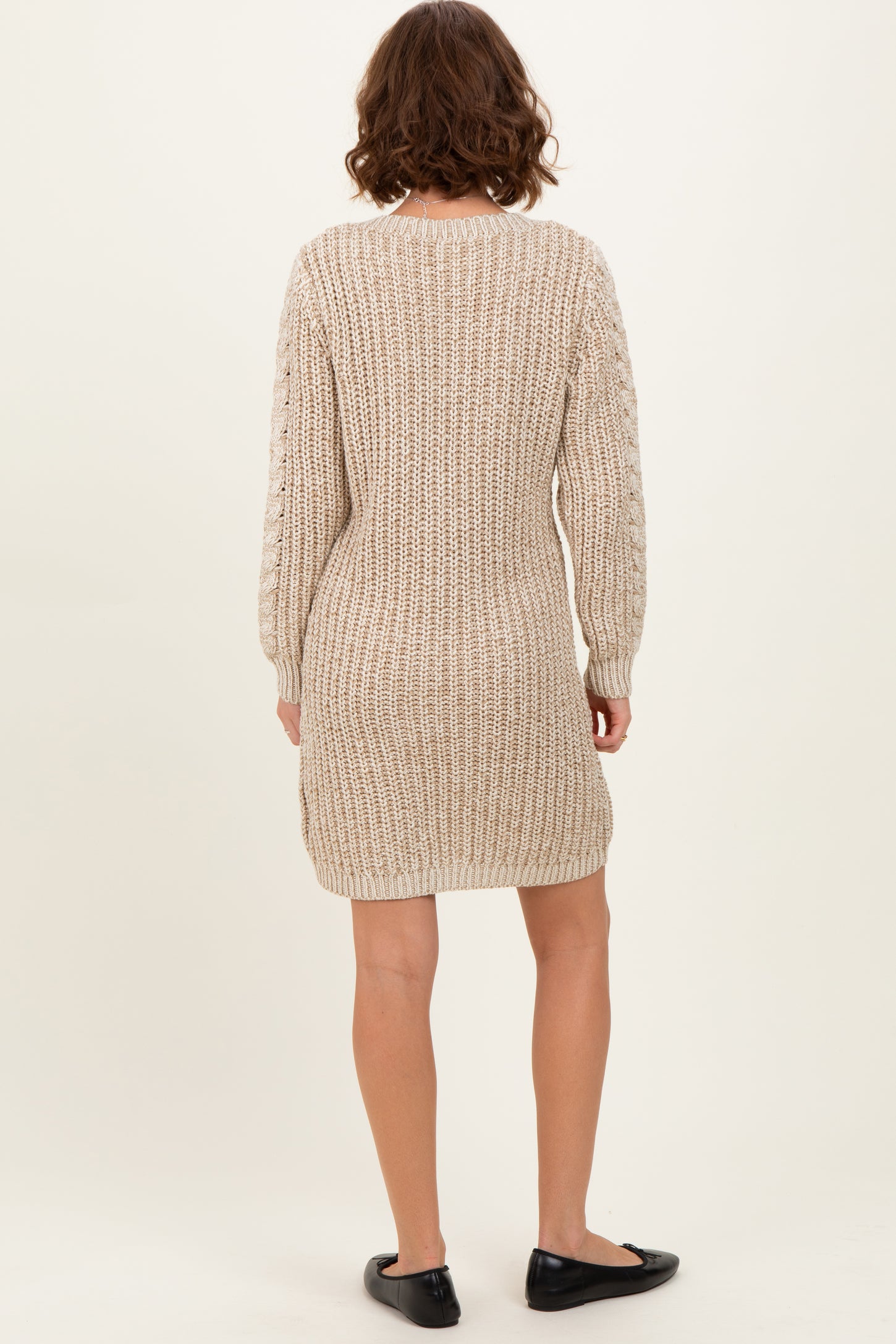 woman wearing a beige knitted sweater dress with long sleeves and a relaxed fit, shown from the back