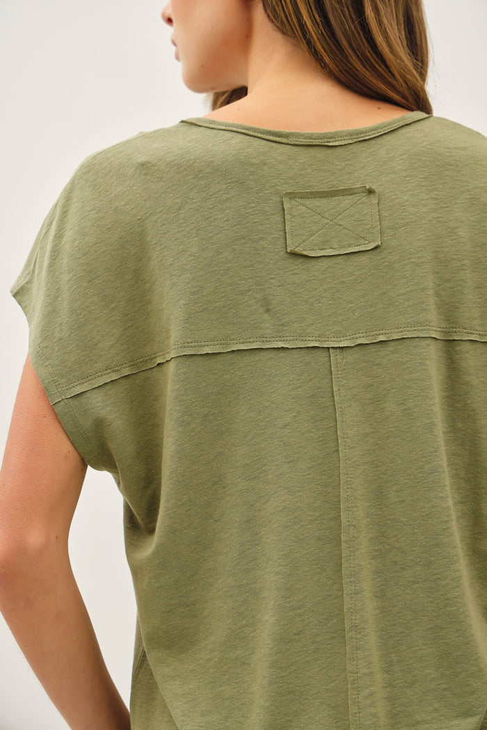 woman wearing an olive green short sleeve top with a back patch detail